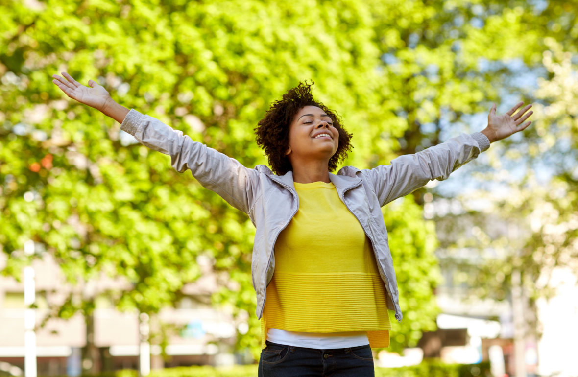 A person standing outdoors with arms open